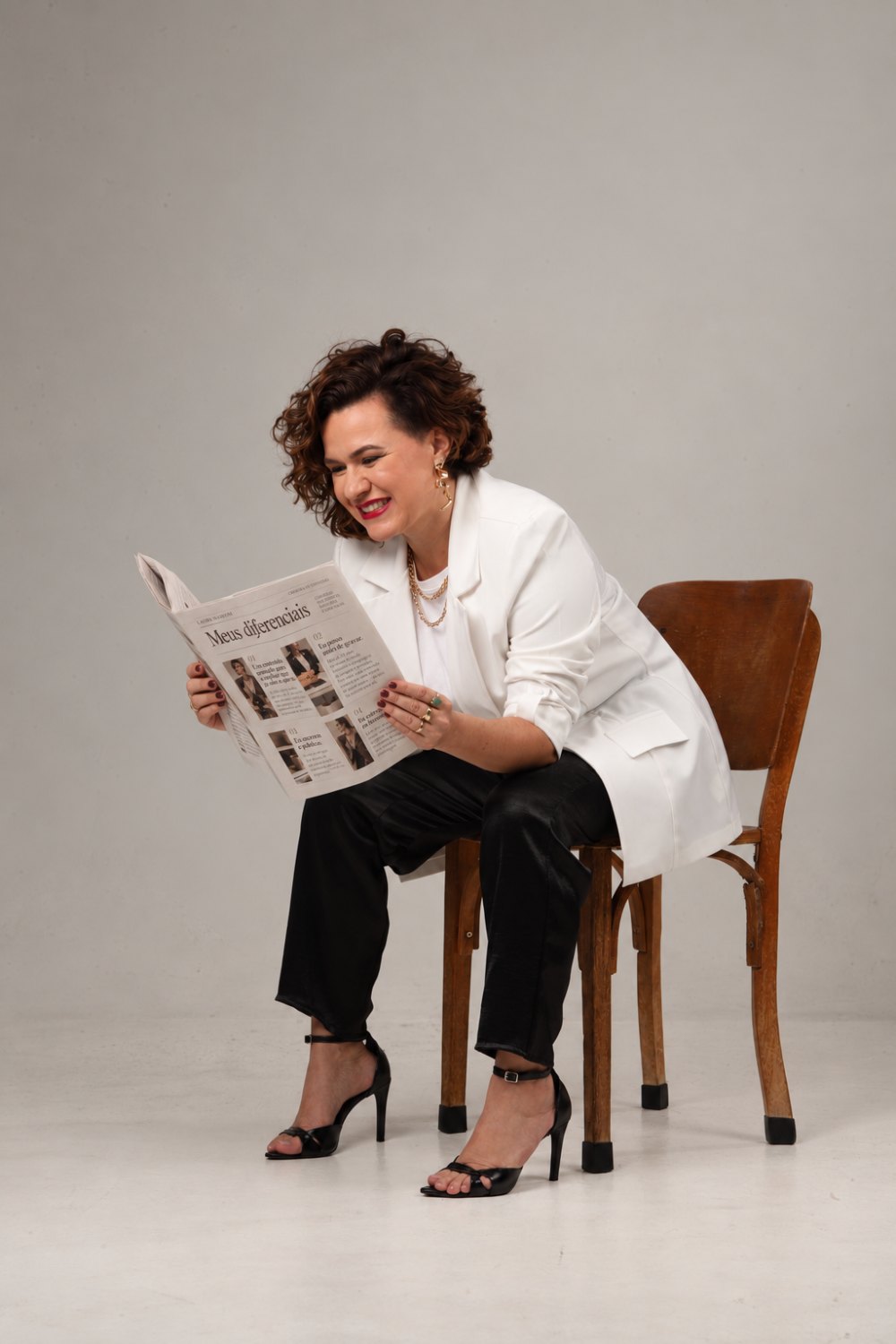 Laura Mareom lendo um jornal, sentada — foto de estúdio