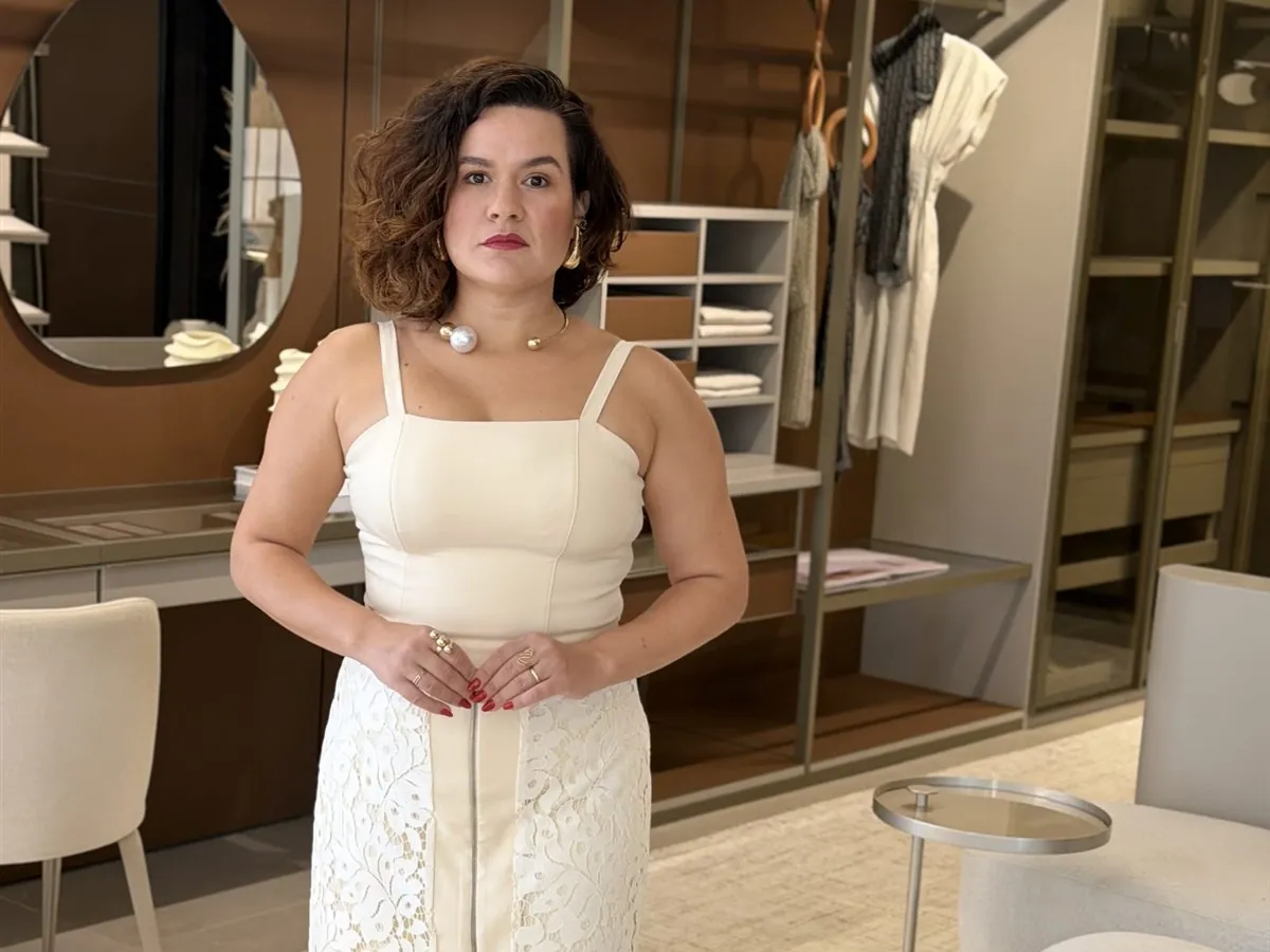 Laura Mareom em um guarda-roupa, com as peças ao fundo